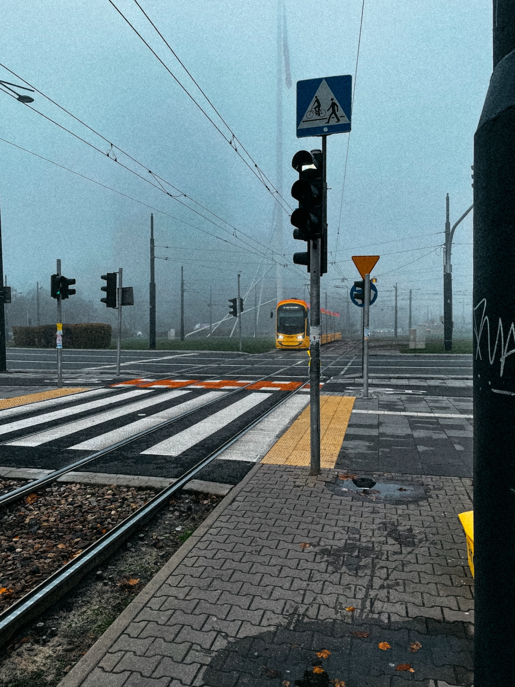 A yellow tram in the fog